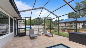 A covered outdoor area with a pool, lounge chairs, and a wooden deck. - Christmas vacation time in Crystal River! Waterfront Pool home. Manatee season!! (Crystal River)