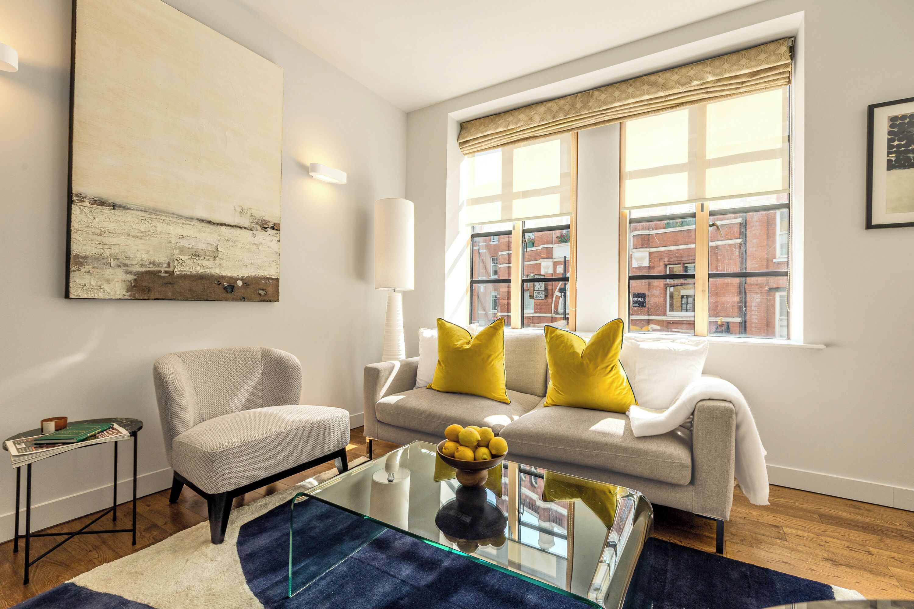 Una sala de estar moderna con un sofá, un sillón y una mesa de centro de vidrio.