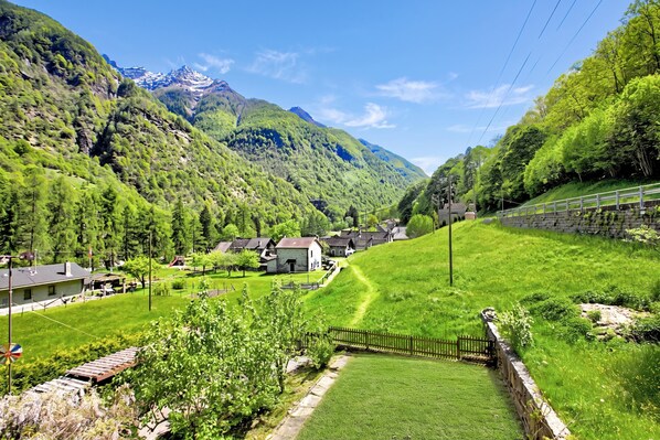 A rural village with houses, a clear sky, and mountains in the background.