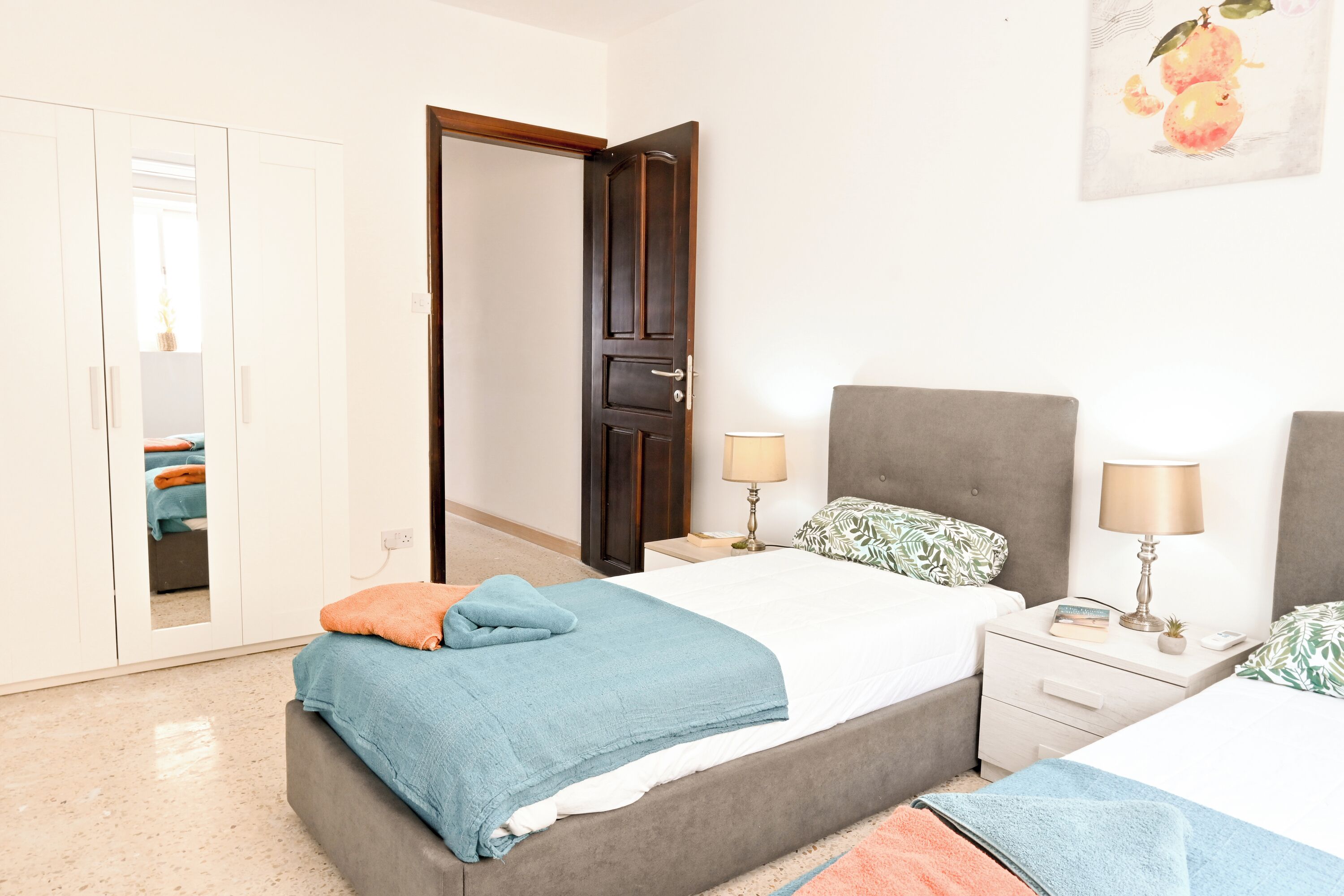 Un dormitorio con una cama, dos mesitas de noche, un armario y una puerta.