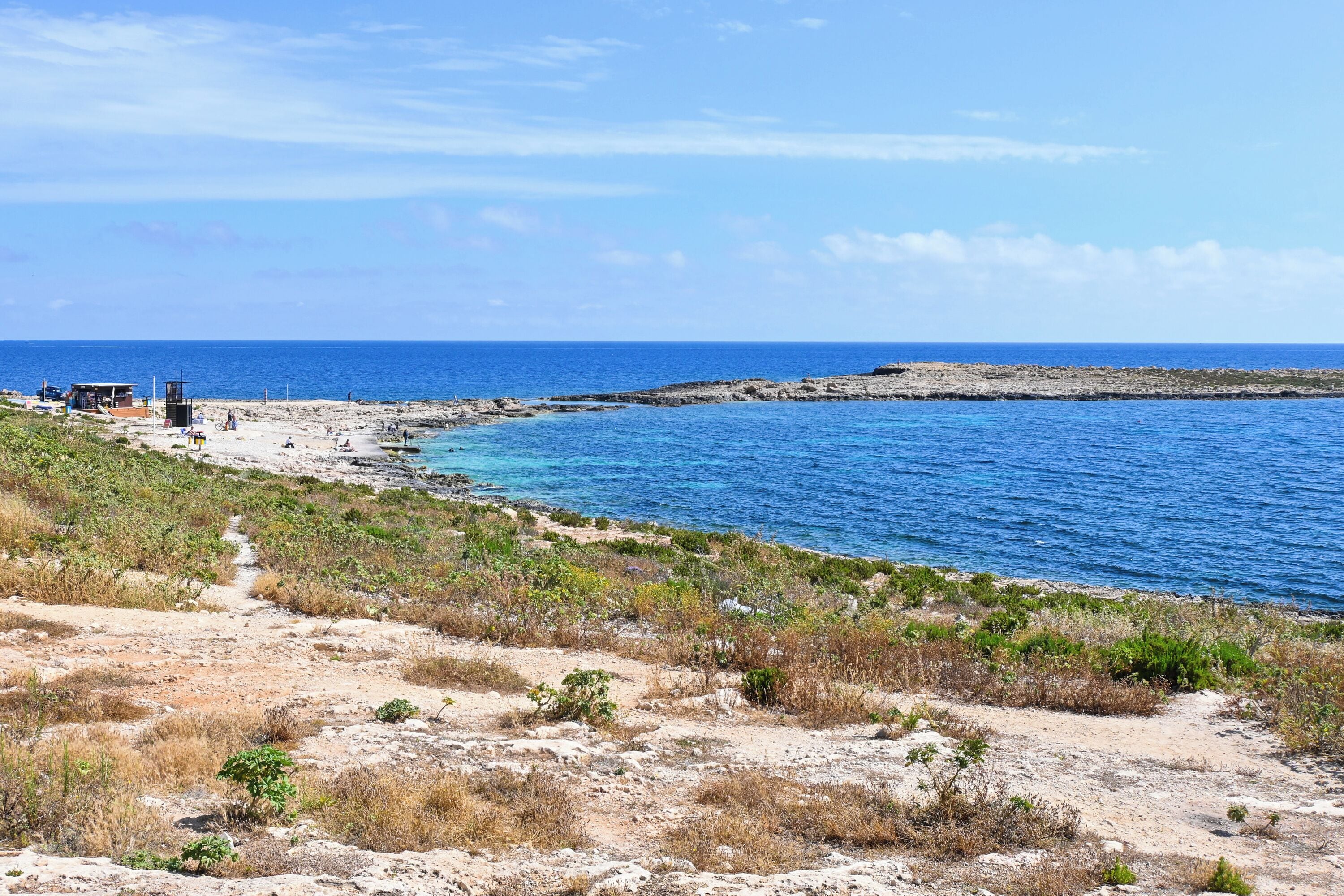 Eine Küstenlandschaft mit Sandstrand, Felsen und blauem Meer.