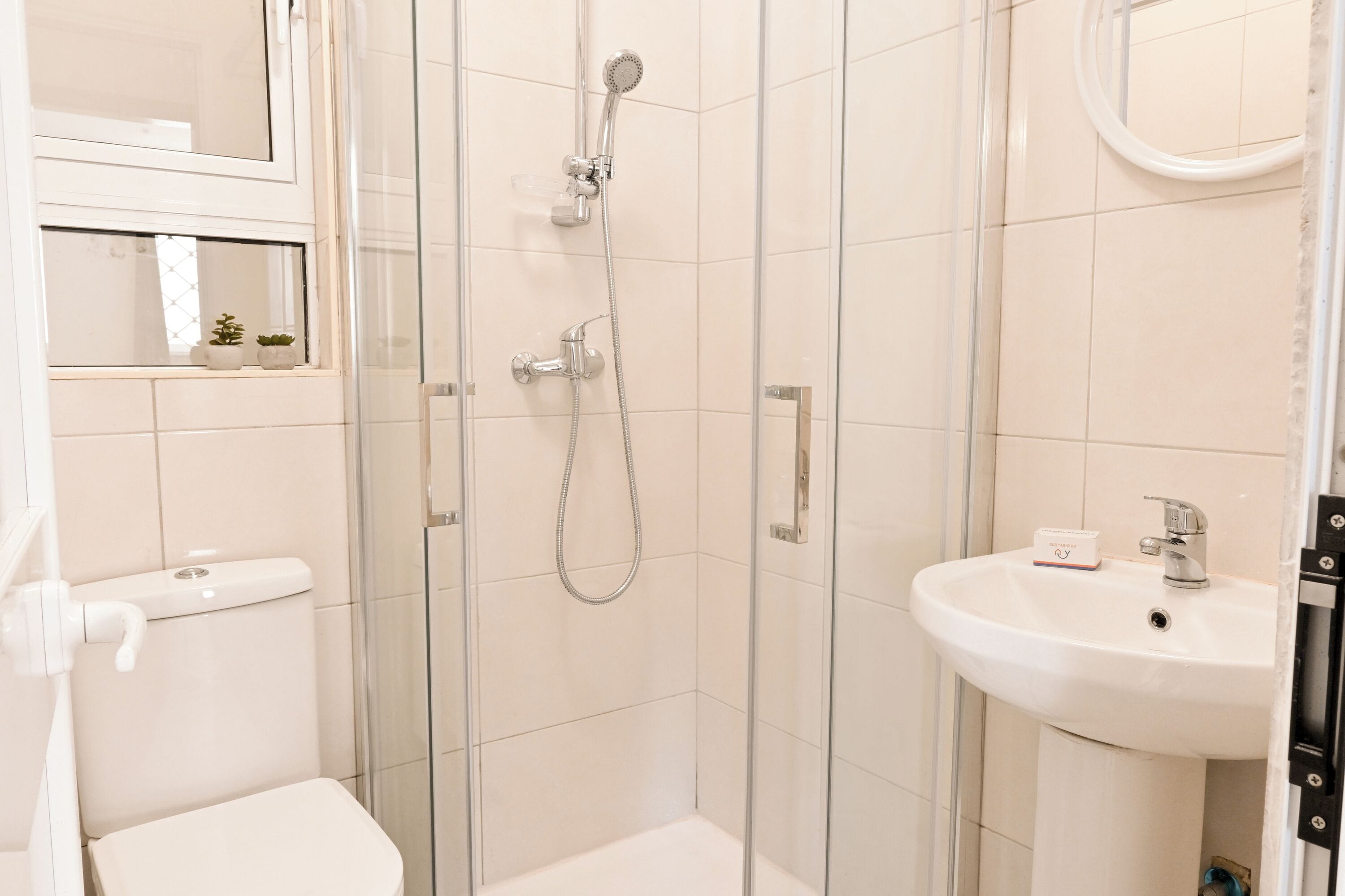 Une salle de bain avec une douche à parois de verre, des toilettes et un lavabo avec un miroir au-dessus.