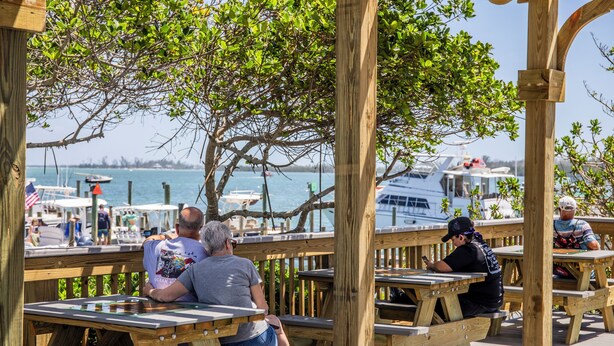 A wooden deck with picnic tables overlooking a marina with boats.