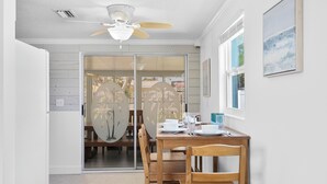 A dining area with a table set for four, a ceiling fan, and a sliding glass door leading to an outdoor patio.