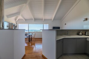 Una cocina moderna con un amplio ventanal, suelo de madera y armarios grises.