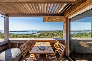 Una terraza de madera con una mesa y sillas que da a un paisaje pintoresco.