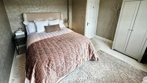 Une chambre à coucher avec un grand lit, une table de chevet, une armoire et une porte.