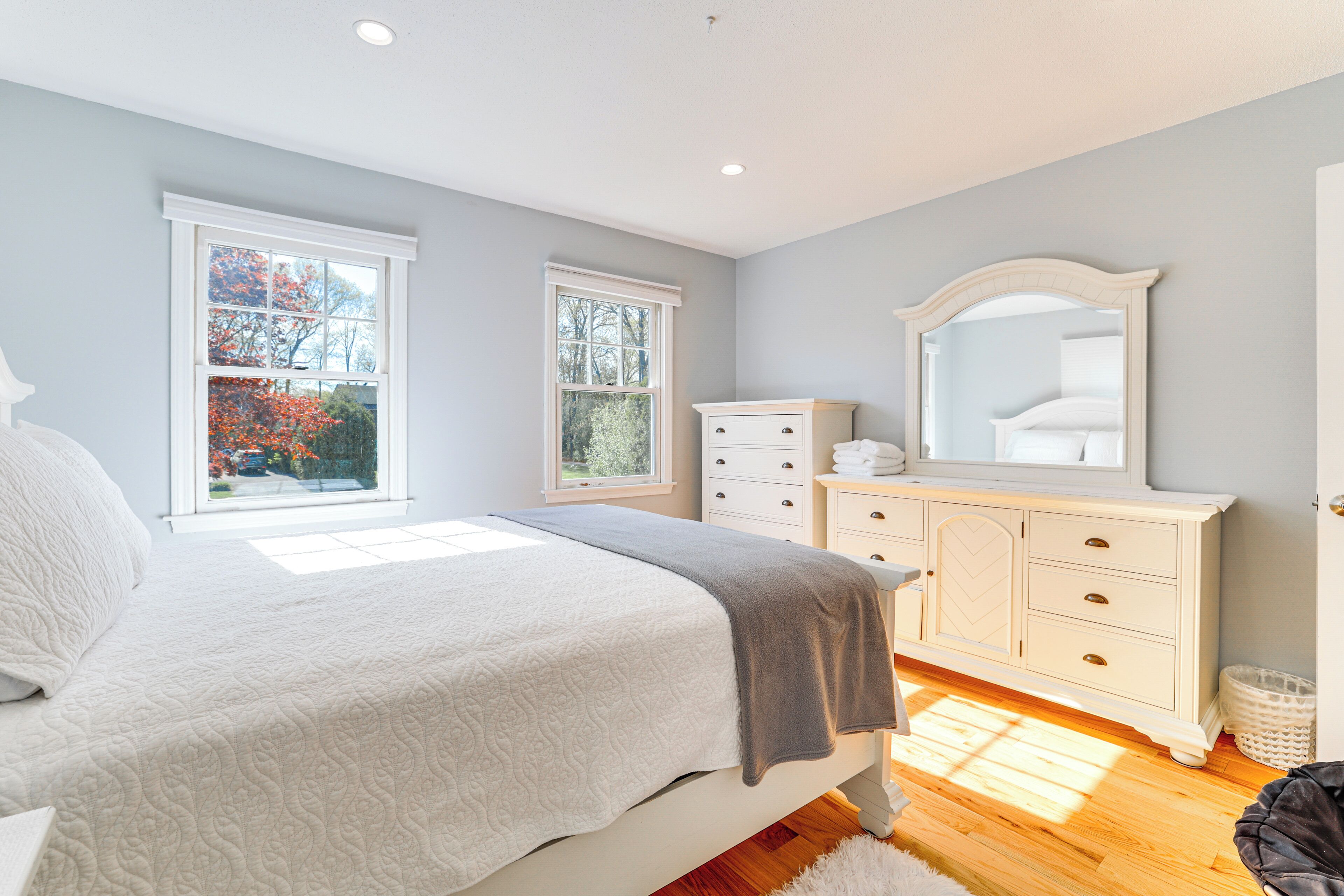 A bedroom with a bed, dresser, and large mirror.