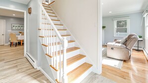 Un intérieur moderne avec un escalier en bois, un espace de vie doté d’un canapé et un coin repas avec une table et des chaises.