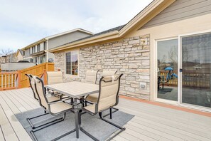 An outdoor patio with a stone wall, a wooden deck, and a table with four chairs. - 5 Mi to Cherry Creek State Park: Cozy Family Home! (Aurora)