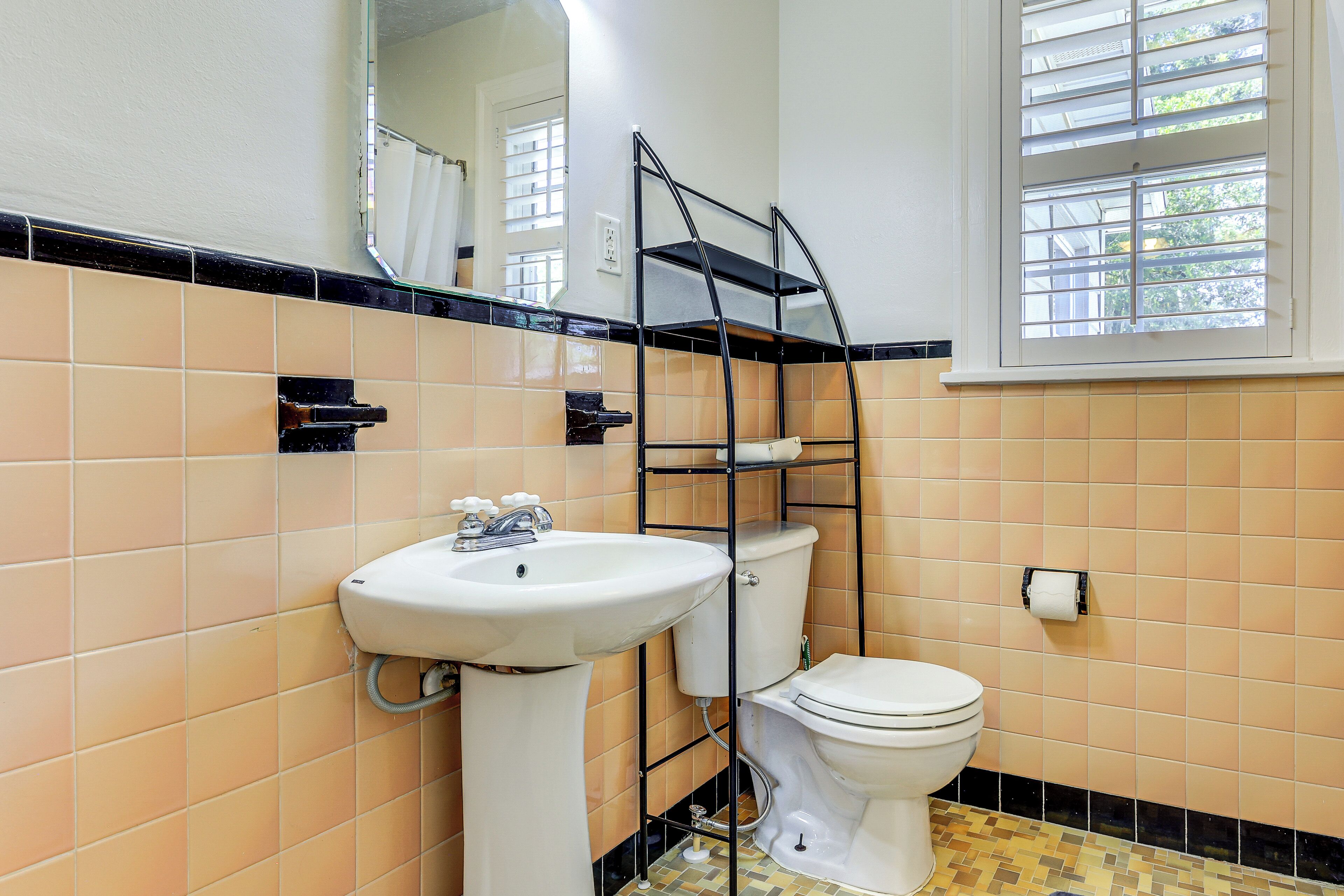 A bathroom with a sink, toilet, and a mirror.