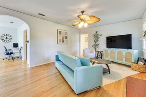 A modern living room with a light blue sofa, a wooden coffee table, a ceiling fan, and a flat-screen TV. - 4 Mi to Dtwn Jacksonville: Chic Home w/ Porch! (Jacksonville)