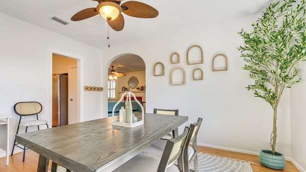 A dining area with a wooden table, cushioned chairs, a ceiling fan, and a potted plant. - 4 Mi to Dtwn Jacksonville: Chic Home w/ Porch! (Jacksonville)