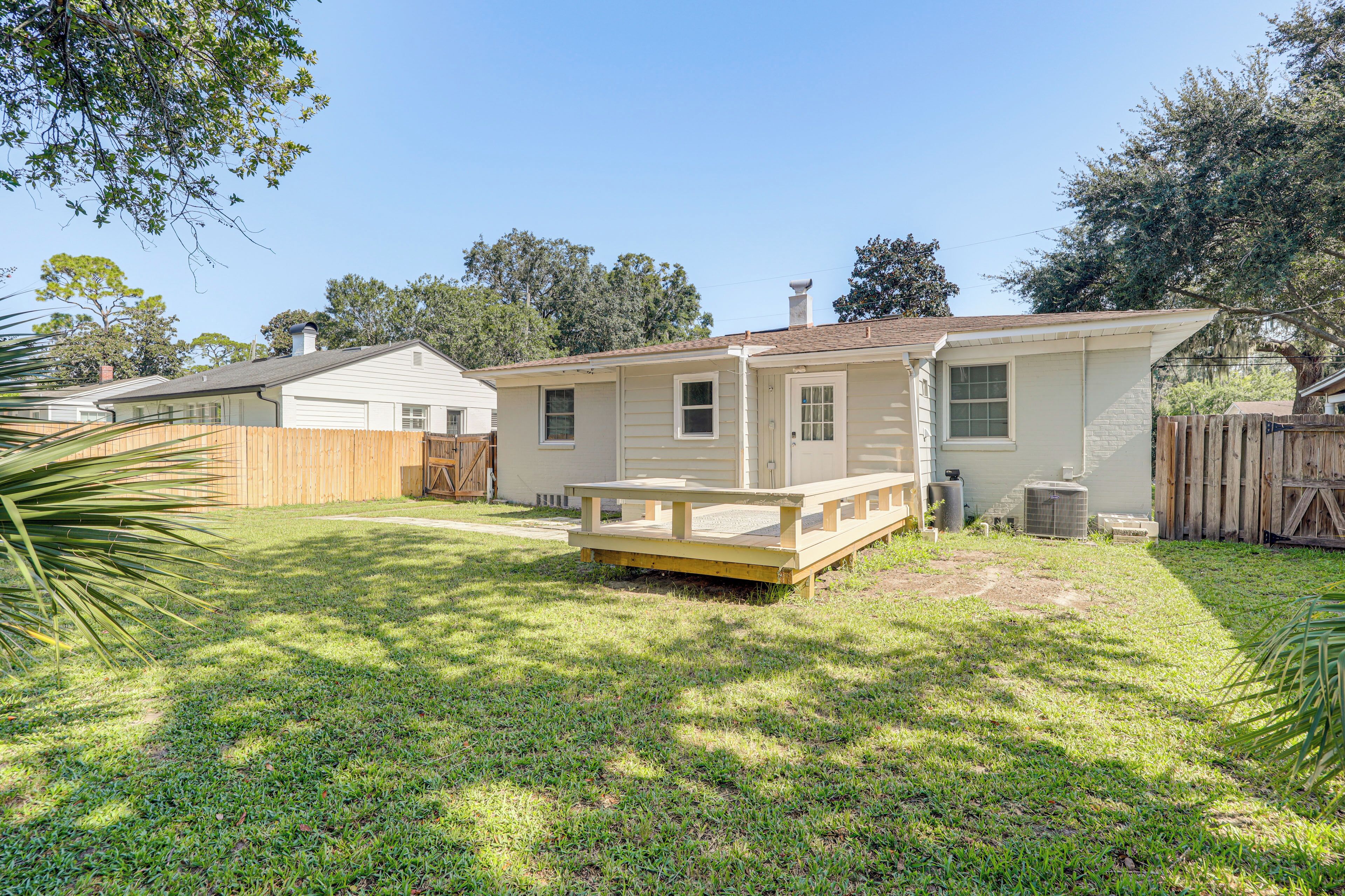 A single-story house with a fenced backyard, a wooden deck, and a small patio area.