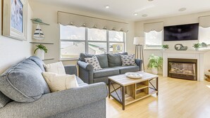 A living room with a grey sofa, a wooden coffee table, and a fireplace. - Ocean Access, Mini Golf & Pools: Jensen Beach Gem (Jensen Beach)