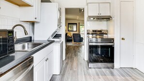 A modern kitchen with white cabinetry, a stainless steel range hood, and a built-in oven. - Condo 9 Mi to Dtwn Dallas: BBQ By the Pool! (Dallas)