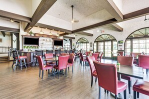 A spacious restaurant with high ceilings, wooden beams, and large arched windows.