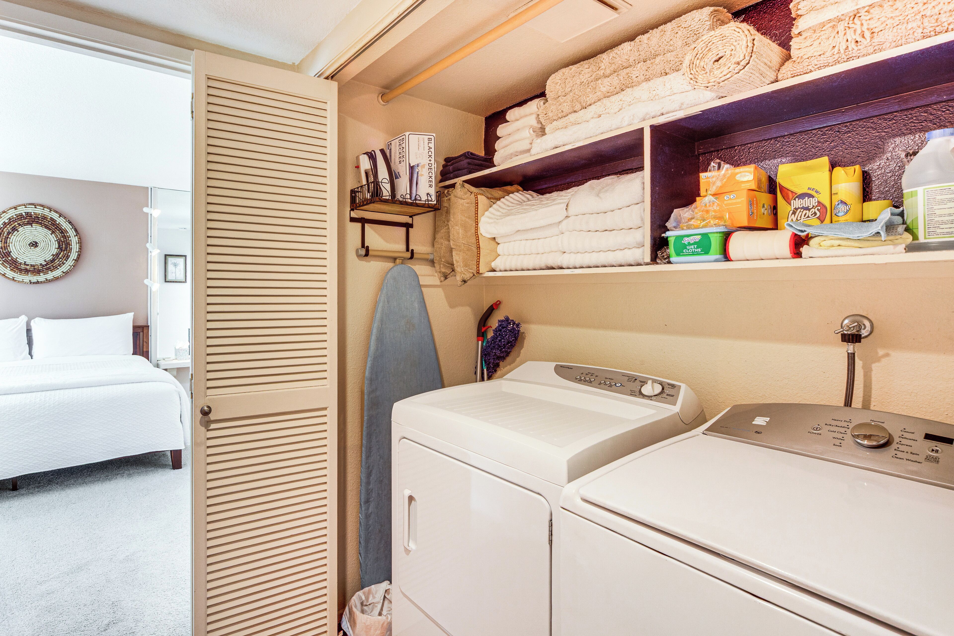 A laundry room with a washing machine, dryer, and neatly stacked towels.