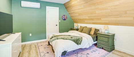 Ein Schlafzimmer mit einem Bett, Nachttisch, Wandlampe und einer wandmontierten Klimaanlage.