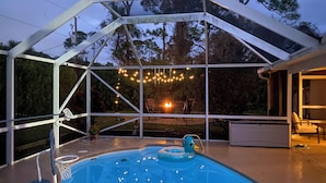 An outdoor swimming pool with a clear view of the surrounding area, including trees and a distant fire. - Pool & Fire Pit: Family-friendly Palm Bay Home! (Palm Bay)
