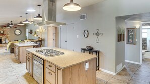 A spacious kitchen with a central island, wooden cabinets, and pendant lighting. - Dog-Friendly Getaway w/ Patio in Tucson! (Tucson)
