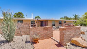 Stunning building with a patio area and brick floor, surrounded by a low wall and a large rock.