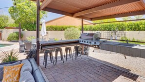 An outdoor patio with a grill, seating area, and a pool in the background. - Dog-Friendly Getaway w/ Patio in Tucson! (Tucson)