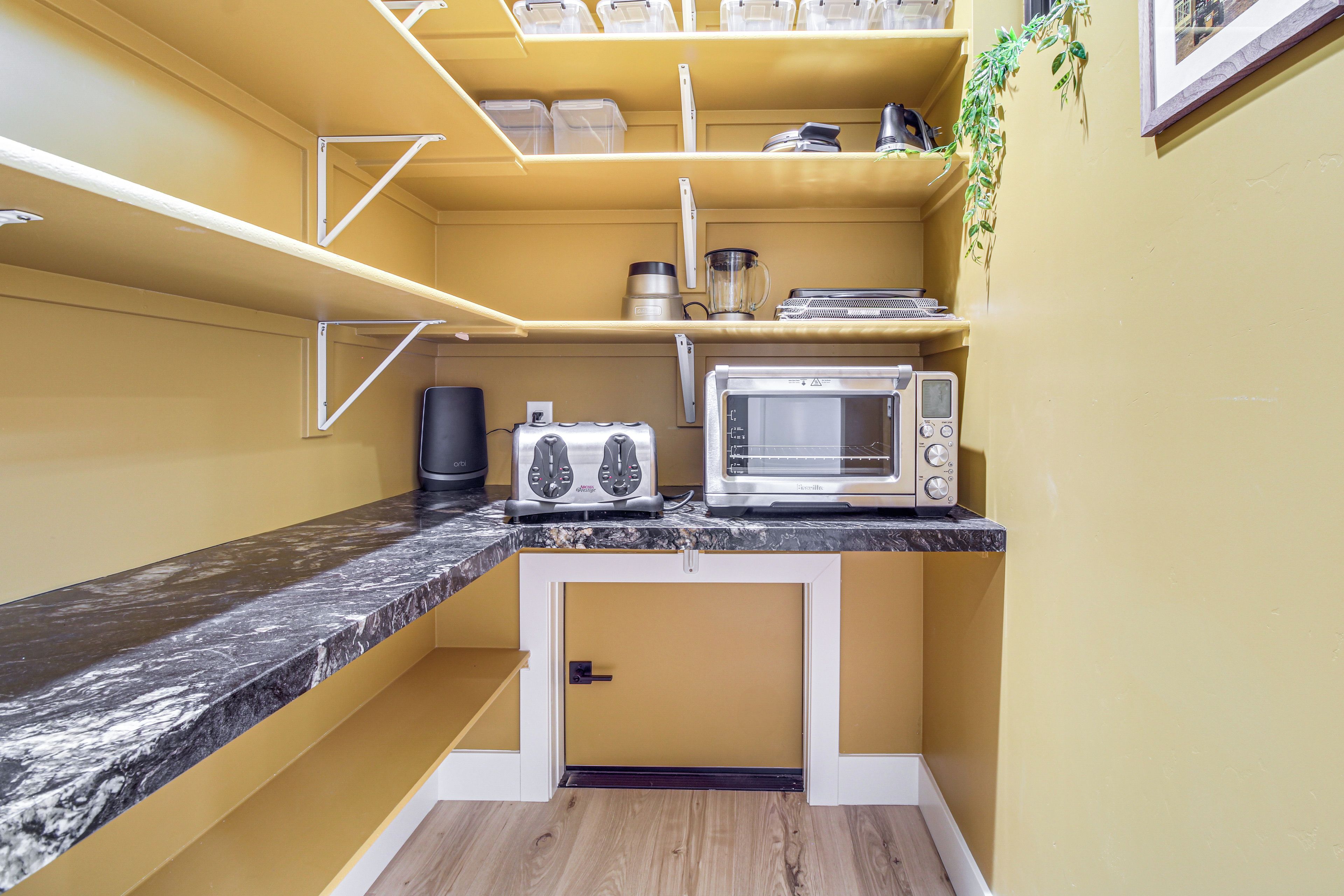 Une cuisine compacte équipée d’un four à micro-ondes, d’un grille-pain et d’étagères de rangement.