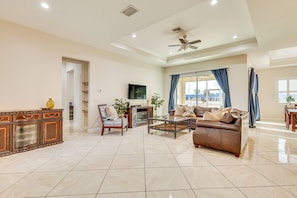 A spacious living room with a leather sofa, a glass coffee table, and a wooden cabinet. - Pet-friendly Home w/ Fenced Yard in Fort Myers! (Fort Myers)