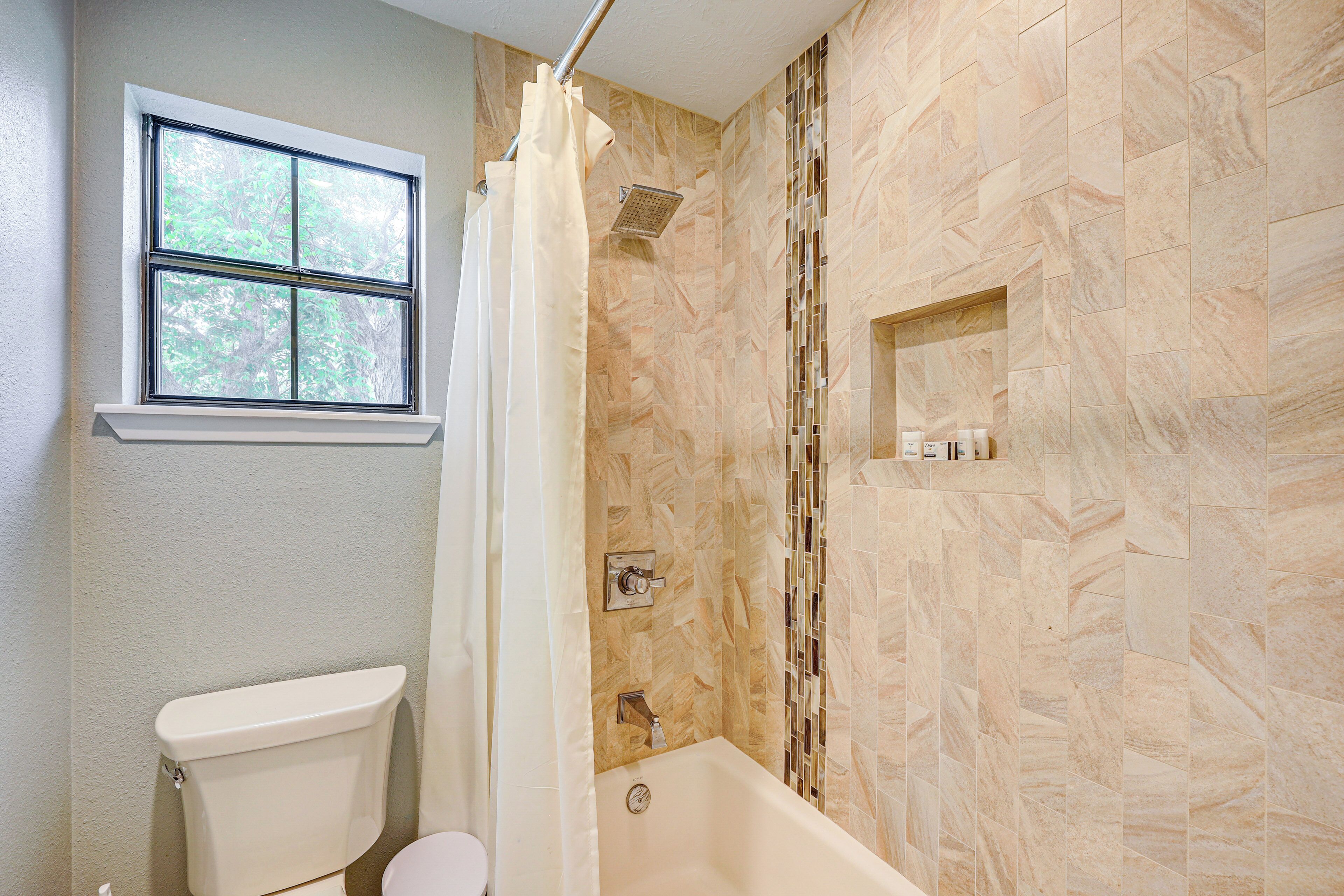 Une salle de bain avec des toilettes, une douche avec un rideau et une fenêtre.