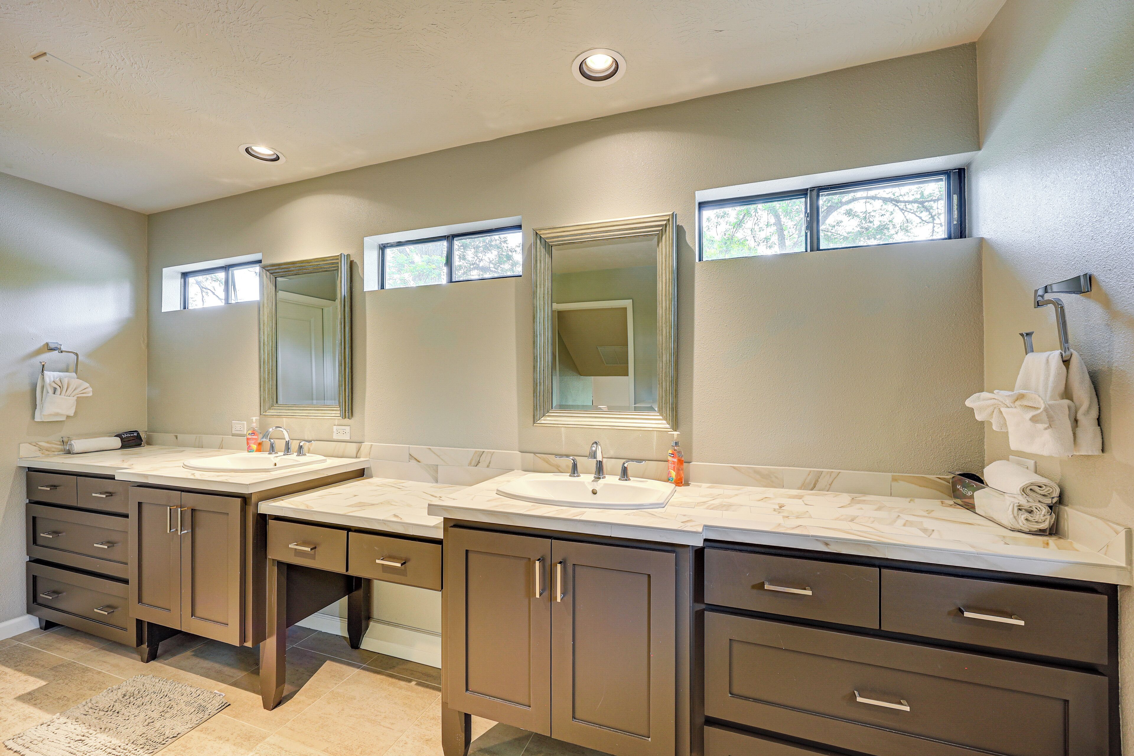 A bathroom with two sinks, mirrors, and cabinets.
