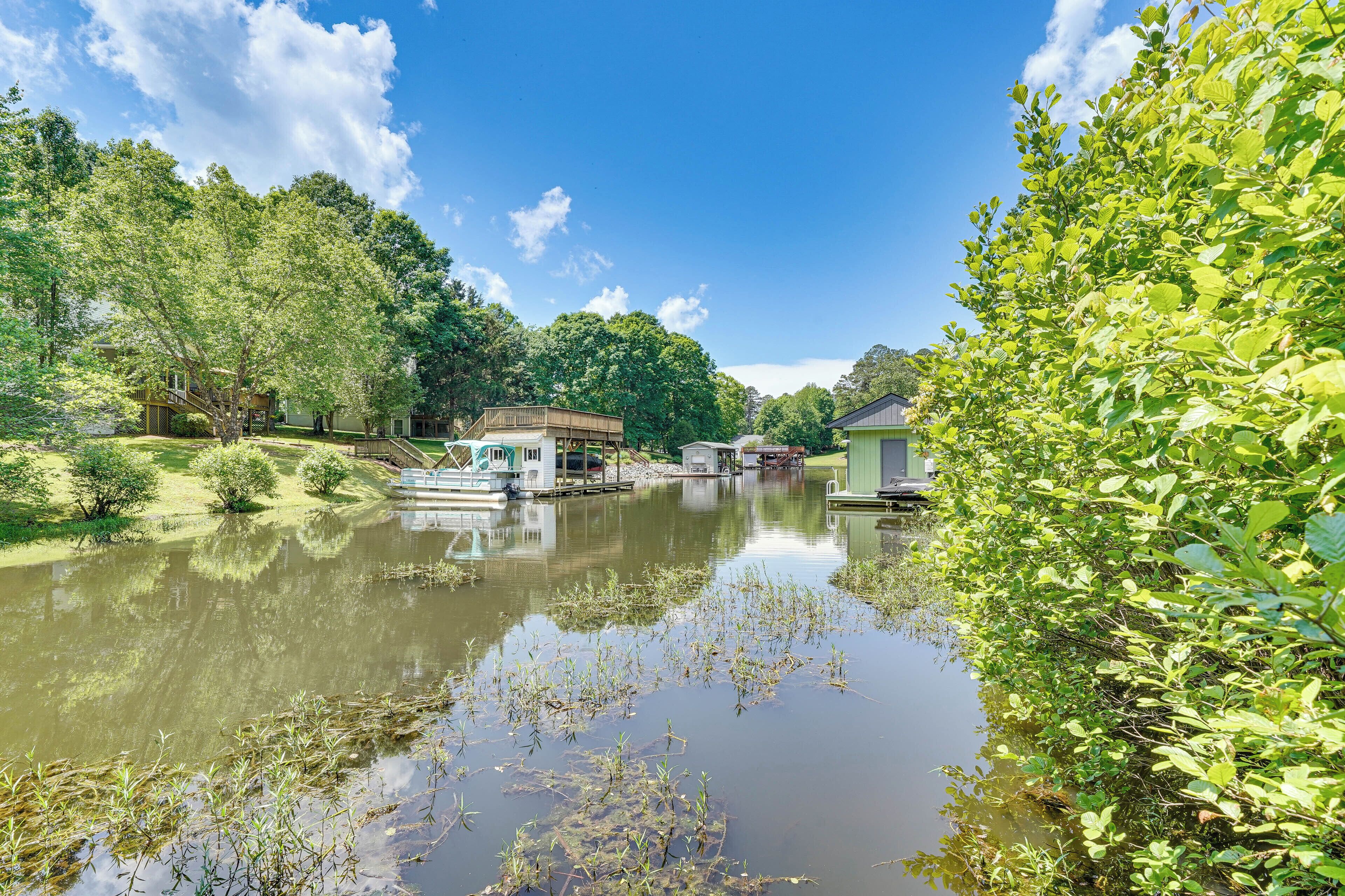A serene riverside scene with a dock, a small building, and lush greenery.