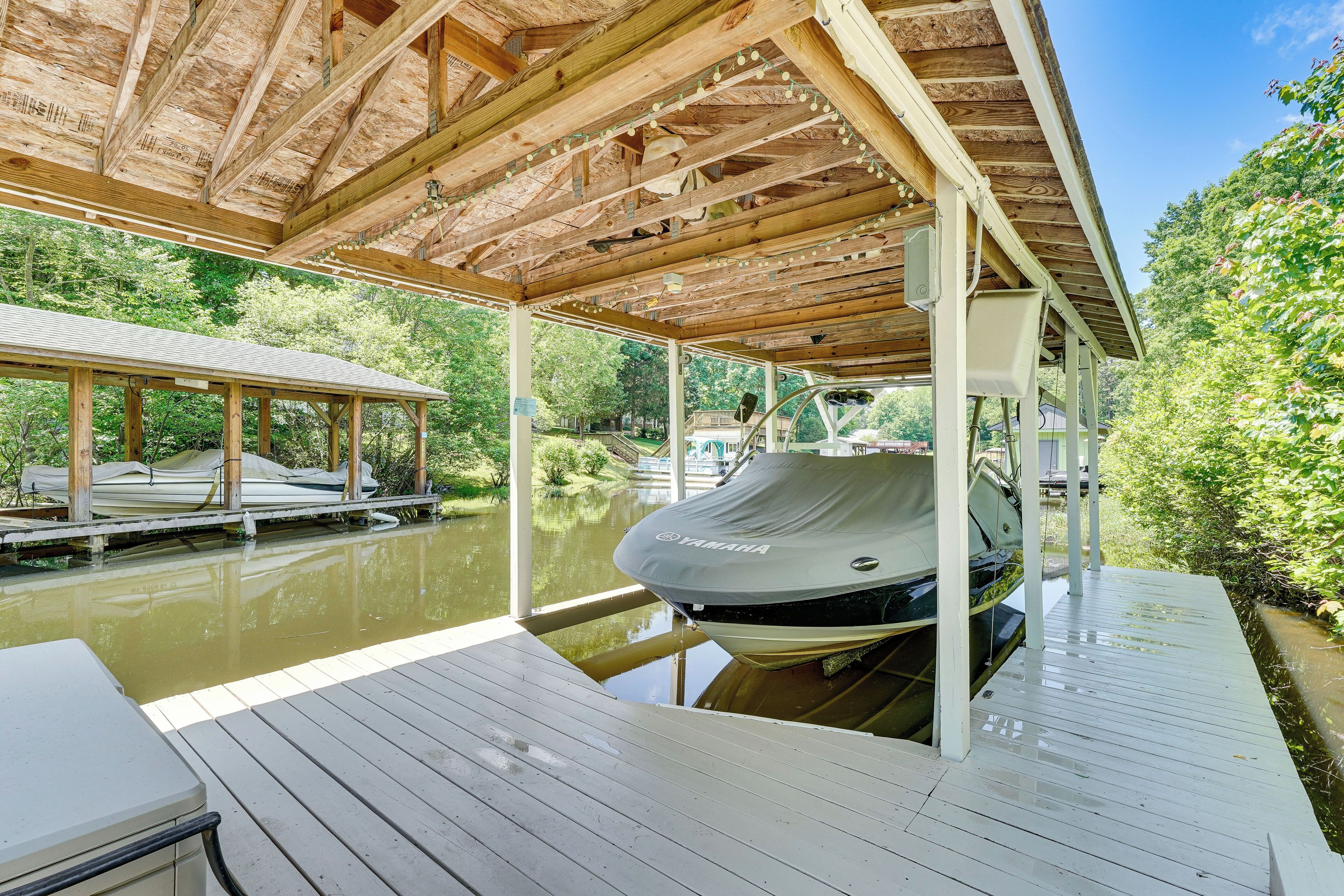 A covered dock area with a boat, wooden deck, and a view of a calm water body.