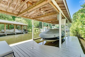 A covered dock area with a boat, wooden deck, and a view of a calm water body. - Private Dock + Fire Pit: Serene Lake Gaston Escape (Henrico)