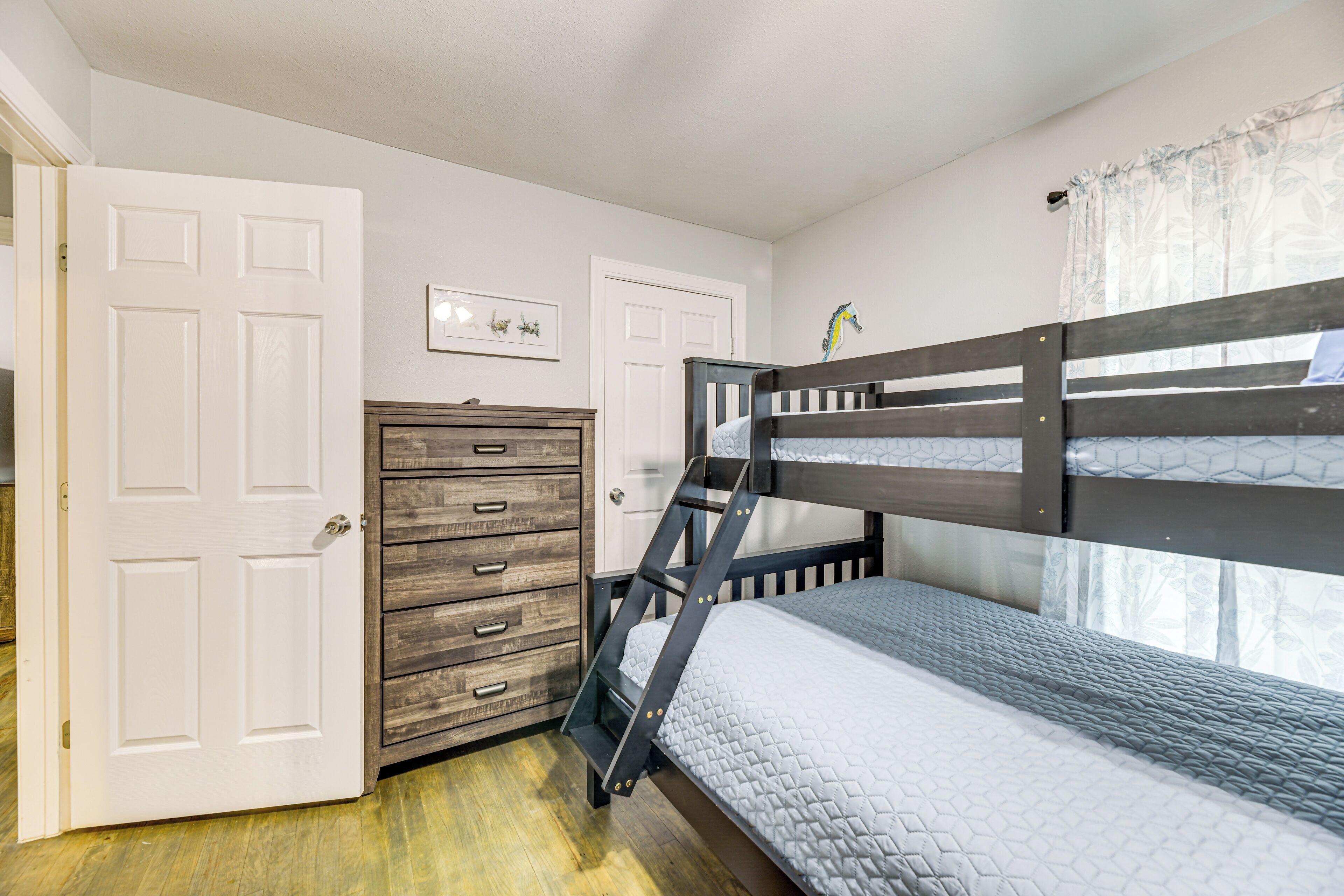 A bedroom with a bunk bed, a wooden dresser, and a door.