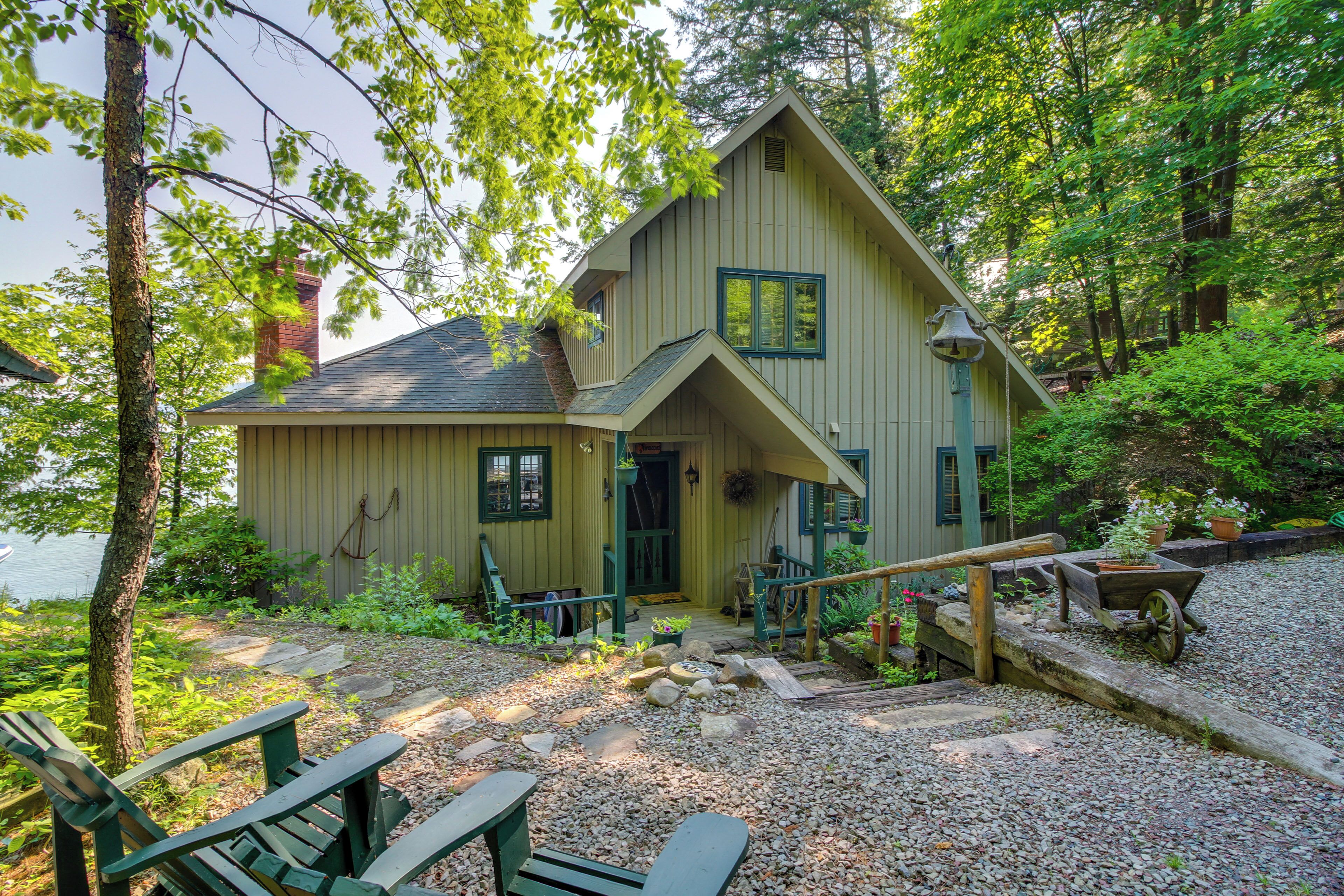 A cabin with a porch, a wooden deck, and a gravel path.