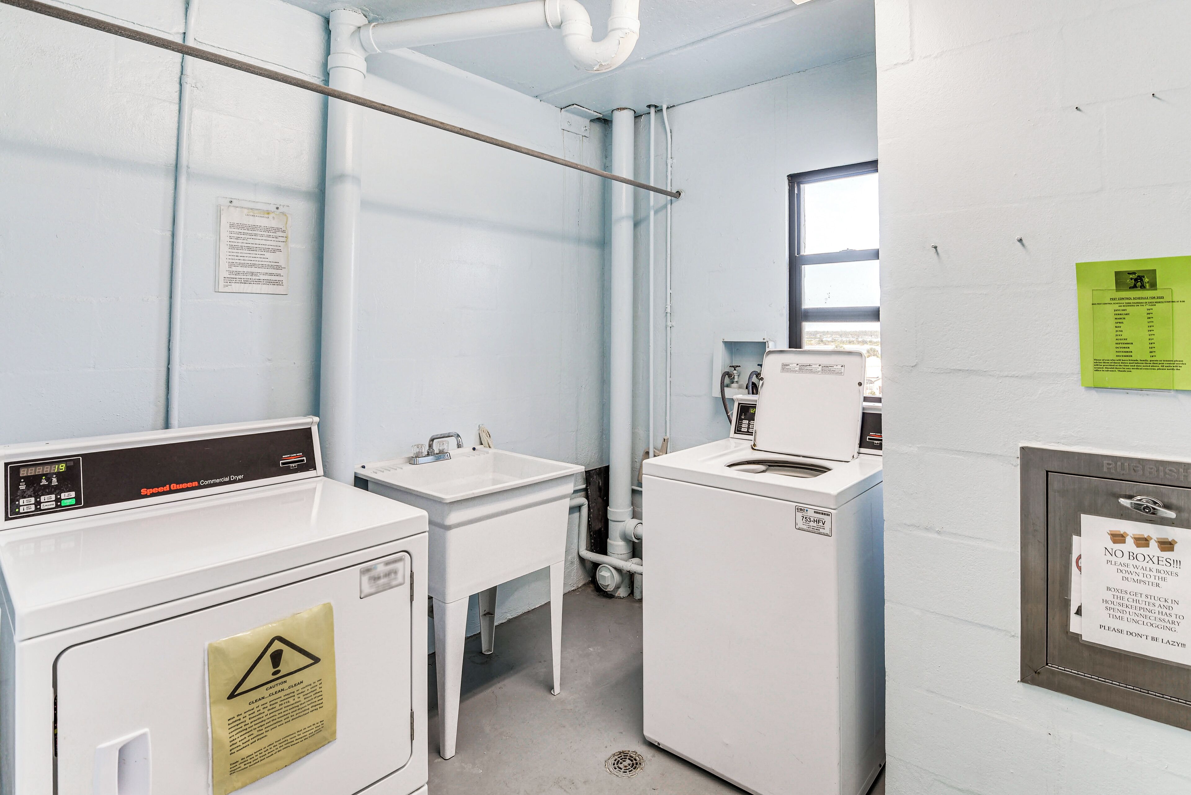 A laundry room with two washing machines, a sink, and a window.