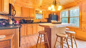 A wooden cabin kitchen with a central island, bar stools, and a large window. - Fish, Hunt, Ride & Ski: 4-season Phillips Retreat (Phillips)