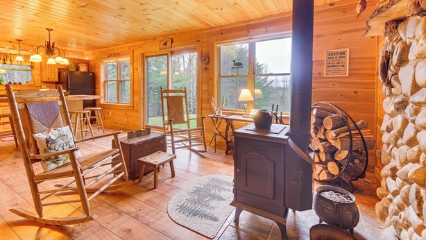 A cozy cabin interior with wooden walls, a fireplace, a dining area, and a kitchen. - Fish, Hunt, Ride & Ski: 4-season Phillips Retreat (Phillips)