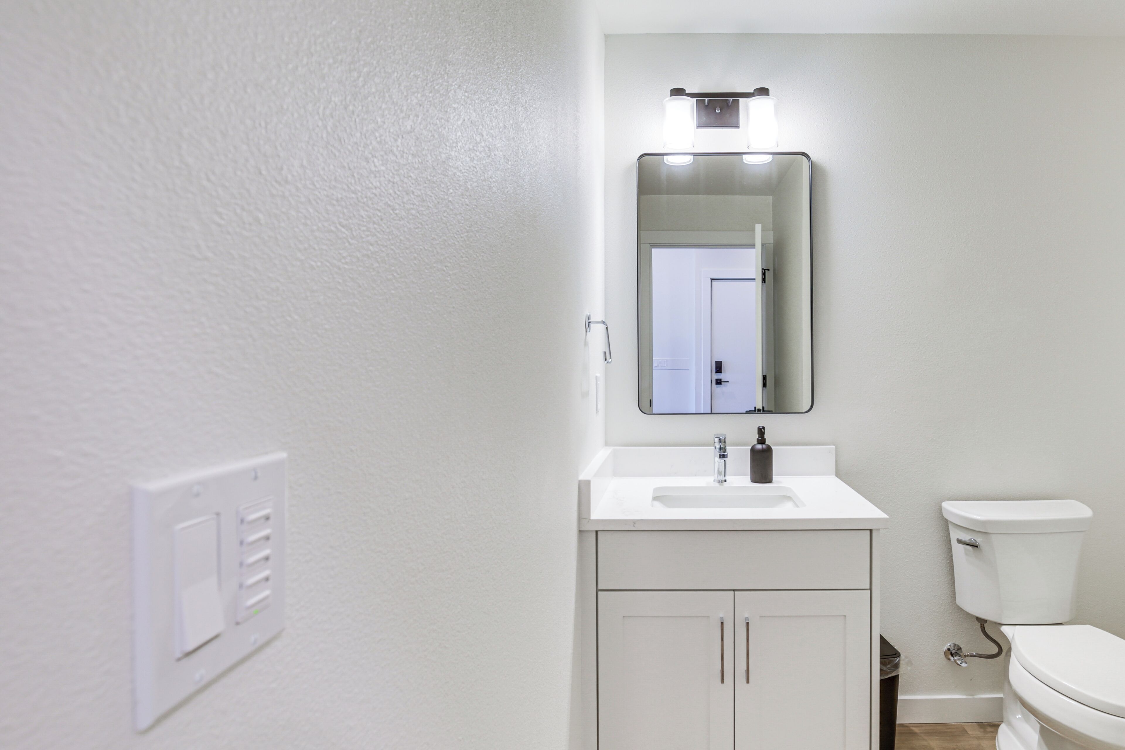 A bathroom with a white sink, mirror, and toilet.