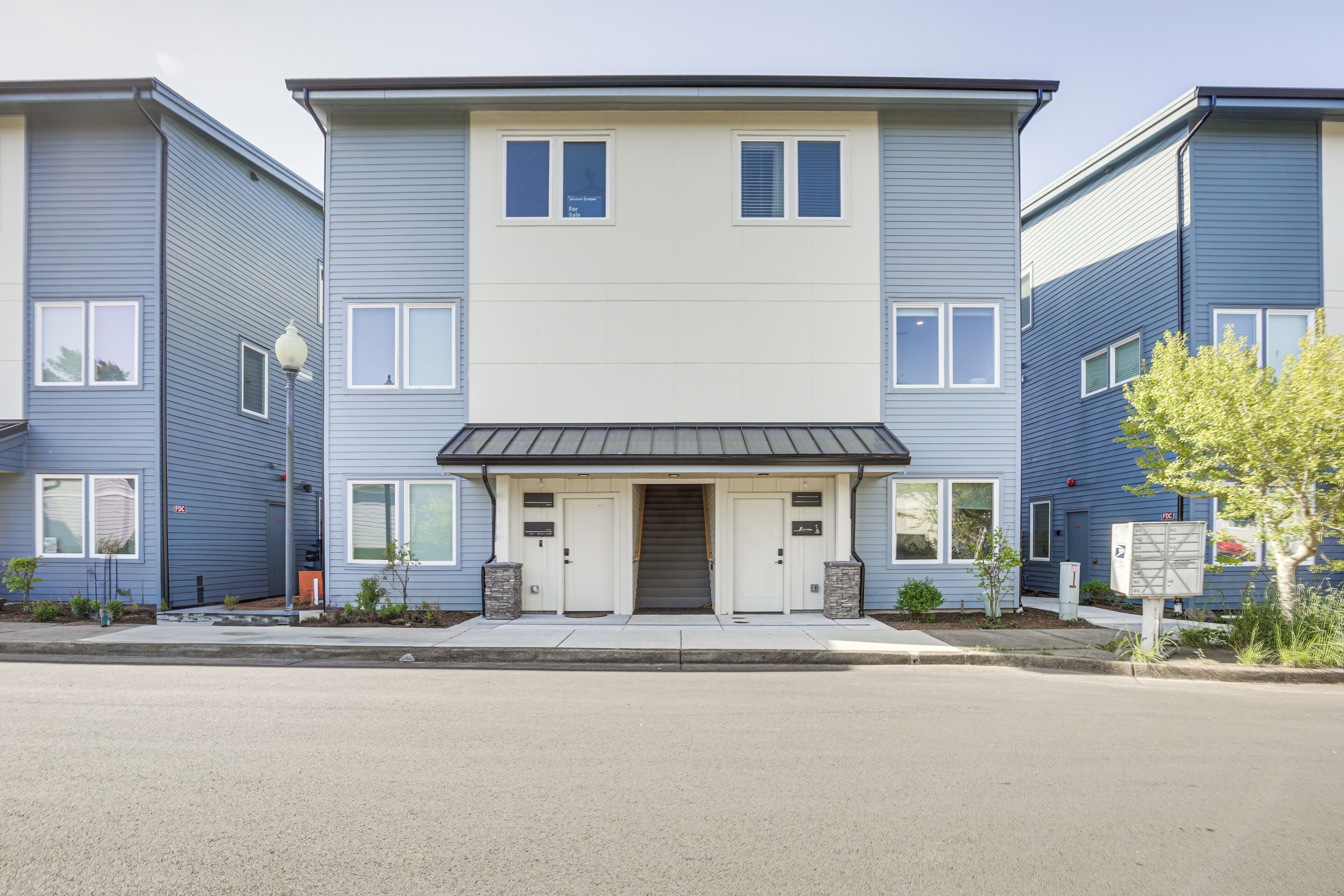 A two-story residential building with a central entrance, two side entrances, and a small porch area.