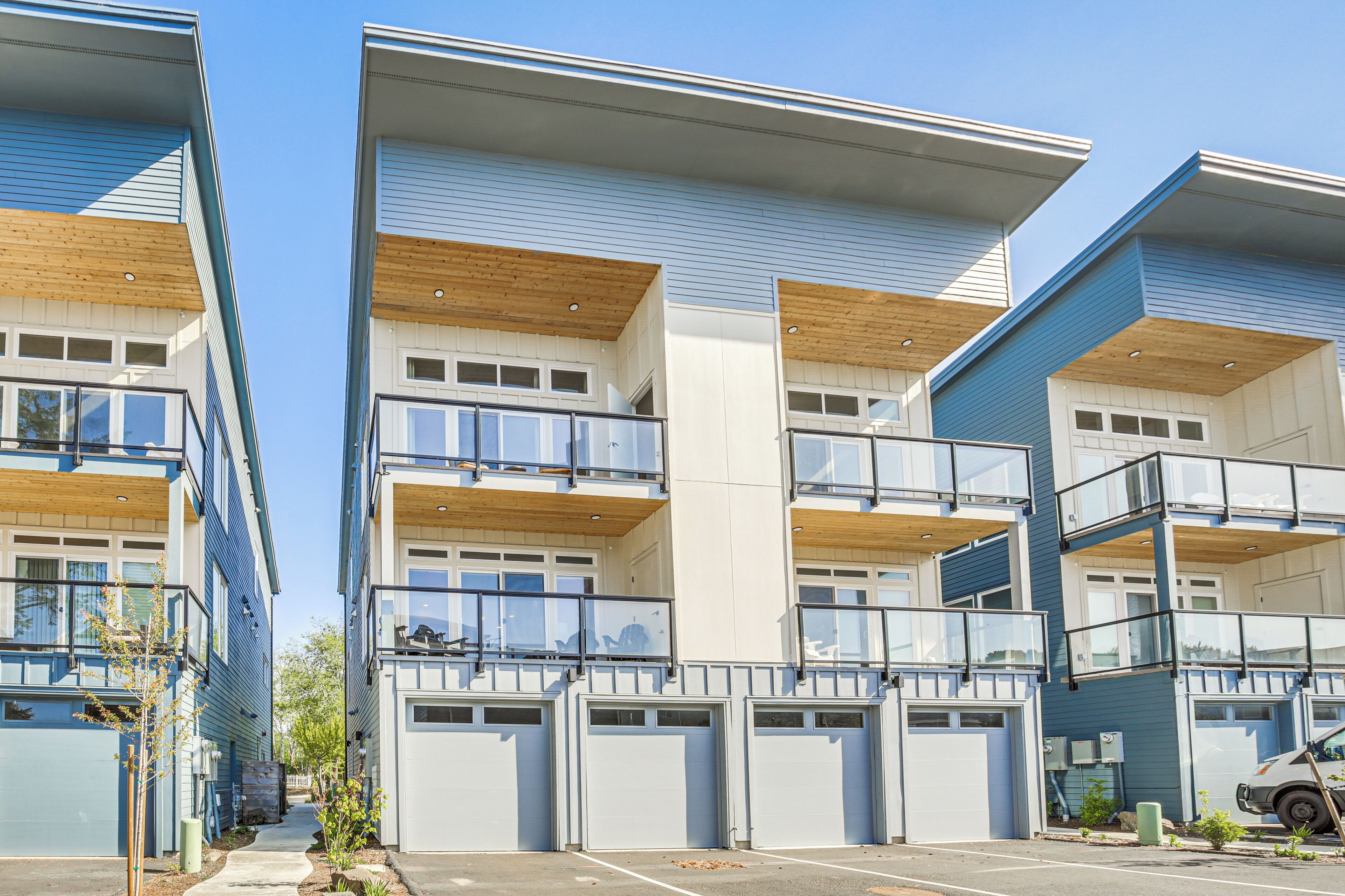Un immeuble résidentiel moderne à plusieurs étages, doté de balcons, de grandes fenêtres et d’une entrée de garage.