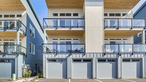 A multi-story residential building with a modern design, featuring balconies, large windows, and garage doors. - Walk to Beaches: 'siletz Bay Bliss' Townhome (Lincoln City)