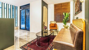 Una sala de estar moderna con una mesa de centro de vidrio, un sofá de cuero marrón y una alfombra estampada.