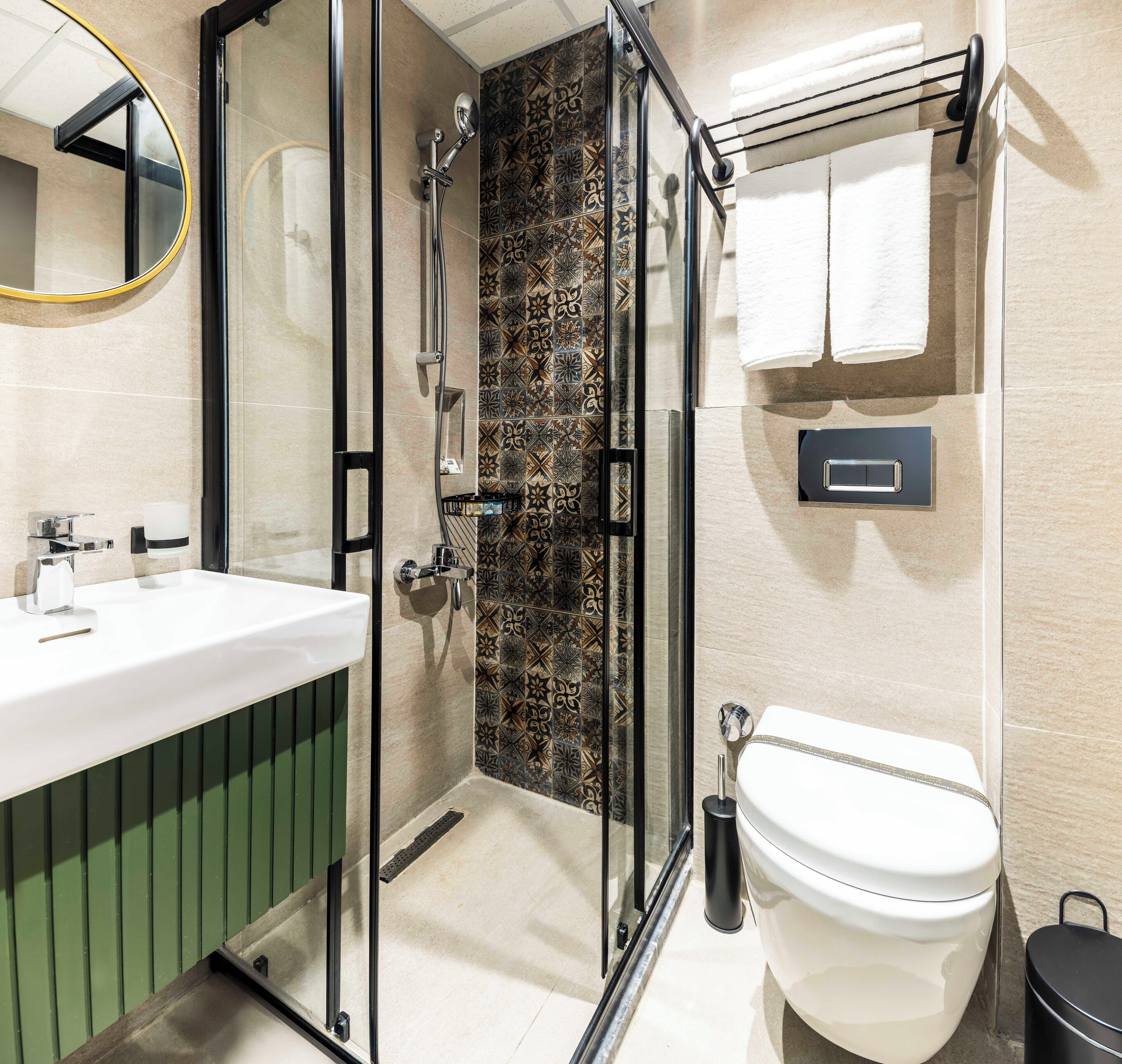 Une salle de bain moderne avec une douche à parois de verre, un lavabo blanc et des toilettes.