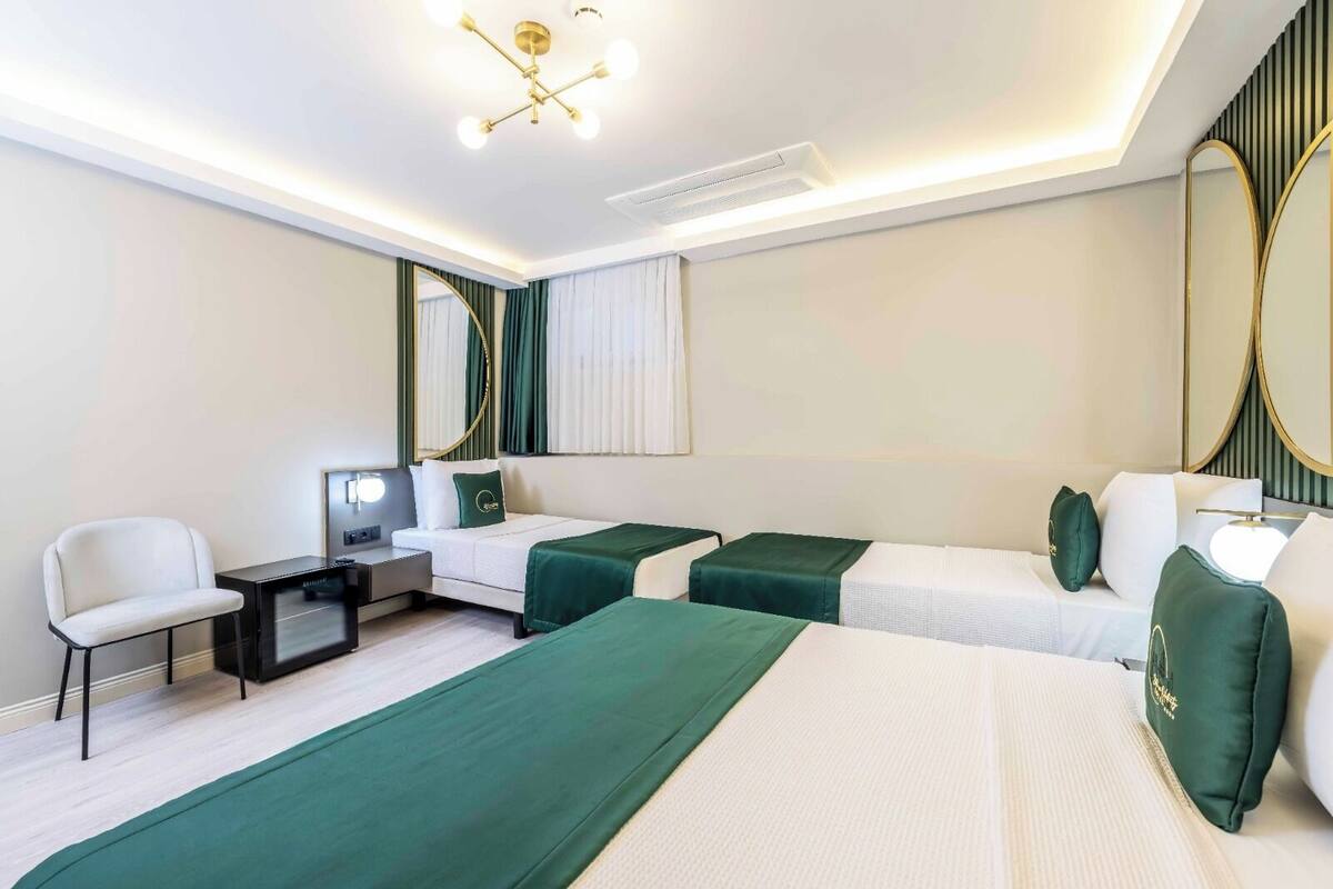 Une chambre d’hôtel avec deux lits, un bureau, une chaise et un grand miroir.