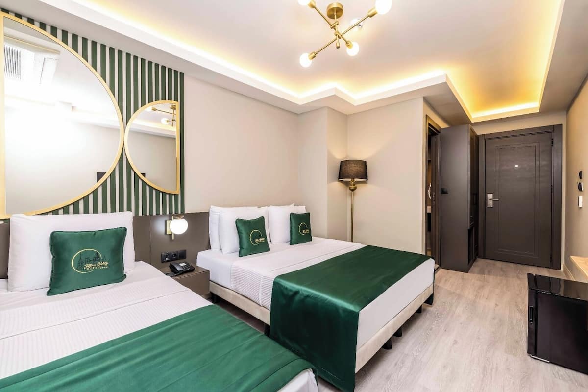 Une chambre d’hôtel avec deux lits, un bureau, un miroir et une lampe.