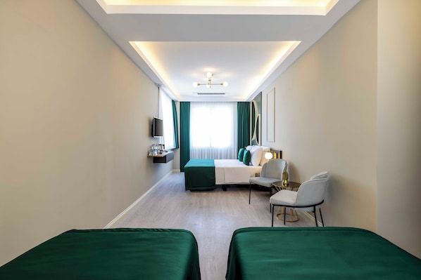 Habitación de hotel con dos camas individuales, un escritorio con silla, televisión y ventana con cortinas.