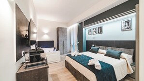 A modern hotel room with a large bed, a bedside table, a mirror, and a wall-mounted TV. - Monteverde Vatican (Rome)