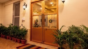 A hotel entrance with double doors, potted plants, and a tiled floor.